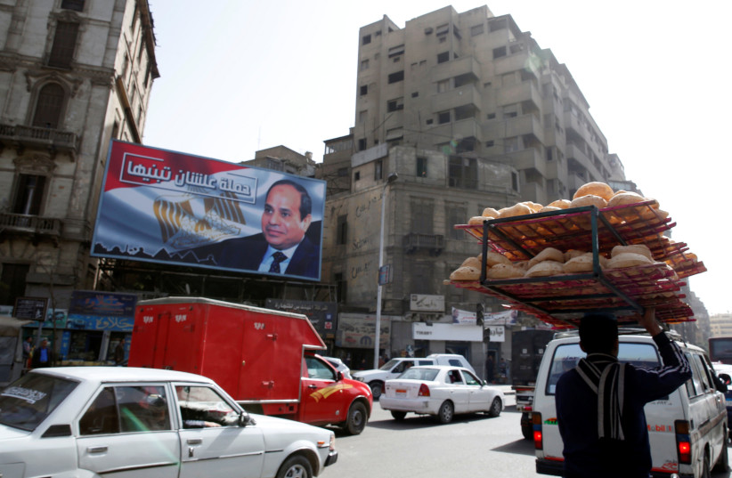 A busy street near a poster of Egypt's President Abdel Fattah al-Sisi from the campaign titled “Alashan Tabneeha” (So You Can Build It), for the upcoming presidential election in Cairo, Egypt, January 22, 2018. (photo credit: REUTERS)