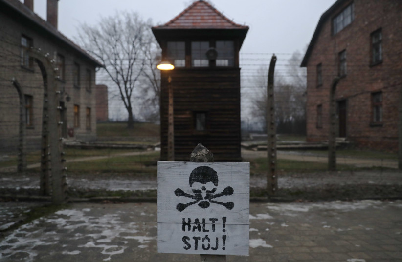A sign reading "Stop" in German and Polish is placed outside the gates to Auschwitz to mark the anniversary of its liberation, January 2018 (photo credit: KACPER PEMPEL/REUTERS)