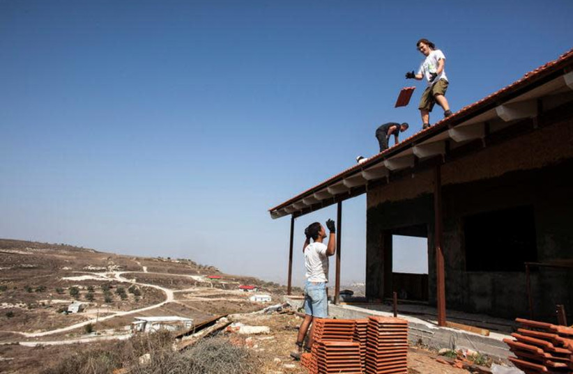 Men work on the roof of a house under construction in the outpost of Havat Gilad, south of the West Bank city of Nablus, November 5, 2013. REUTERS/Nir Elias/File Photo (photo credit: REUTERS/NIR ELIAS)