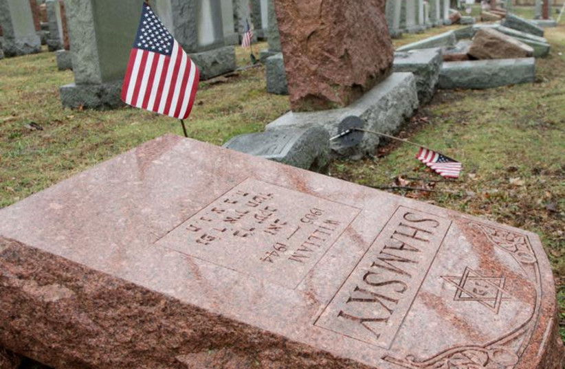 An American flag still stands next to one of over 170 toppled Jewish headstones after a weekend vandalism attack on Chesed Shel Emeth Cemetery in University City, a suburb of St Louis, Missouri, U.S. February 21, 2017. (photo credit: REUTERS/TOM GANNAM)