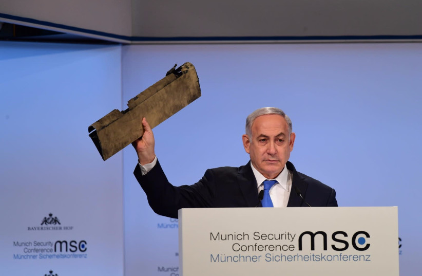 Prime Minister Benjamin Netanyahu holds up part of Iranian drone that landed in Israel in February 2018 at the Munich Security Conference, February 18, 2018 (photo credit: AMOS BEN-GERSHOM/GPO)