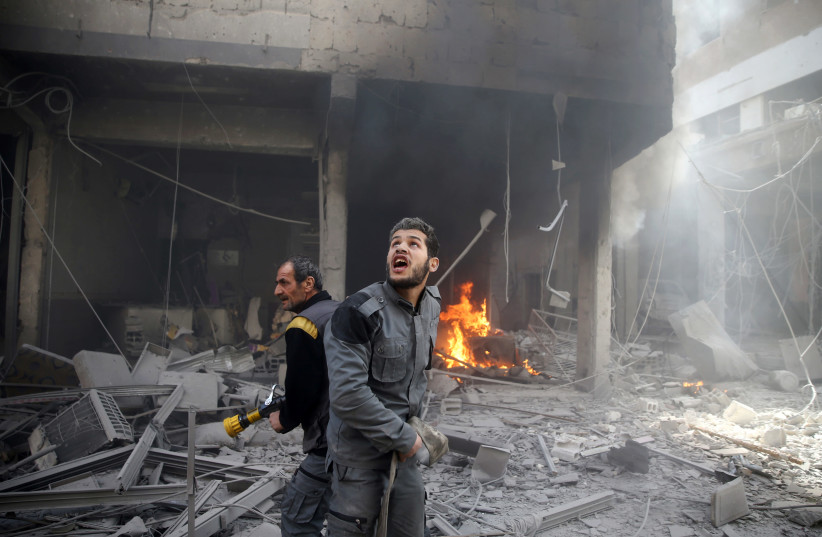 A civil defense member reacts at a damaged site after an airstrike in the besieged town of Douma, Eastern Ghouta, Damascus, Syria (photo credit: REUTERS/BASSAM KHABIEH)