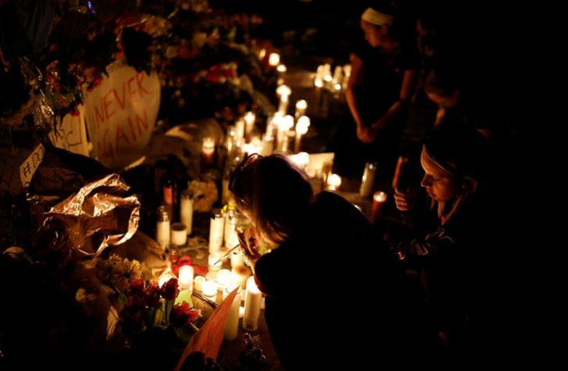 People light candles in front of mementoes placed in front of the fence of the Marjory Stoneman Douglas High School to commemorate the victims of the mass shooting, in Parkland, Florida, U.S., February 21, 2018. REUTERS/Carlos Garcia Rawlins (photo credit: CARLOS GARCIA RAWLINS/ REUTERS)