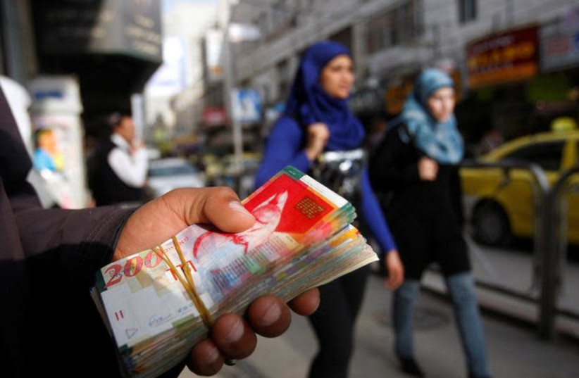 Palestinian women walk past a money changer in the West Bank city of Ramallah February 16, 2010. REUTERS/Mohamad Torokman/File Photo (photo credit: REUTERS/MOHAMAD TOROKMAN)