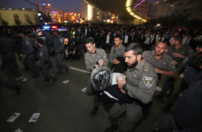 Israel police carry a haredi protestor during an anti-conscription demonstration in Jerusalem, March 2018 (photo credit: MARC ISRAEL SELLEM/THE JERUSALEM POST)