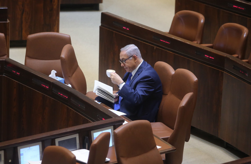 Prime Minister Benjamin Netanyahu reads in the Knesset, March 12, 2018. (photo credit: MARC ISRAEL SELLEM/THE JERUSALEM POST)