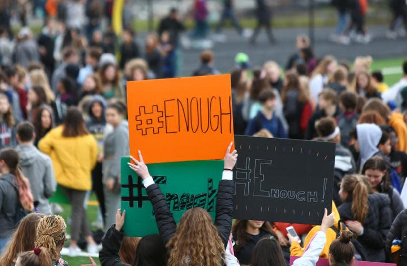 Students hold "#Enough" signs as they participate in the National School Walkout to protest gun violence in the U.S, March 14, 2018 (photo credit: REUTERS/LINDSEY WASSON)