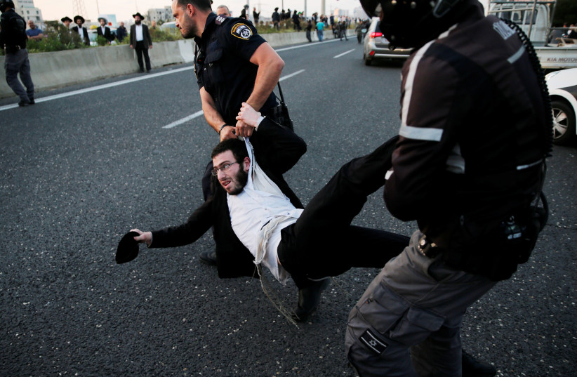 An Israeli ultra-Orthodox Jew is being carried away by police after blocking a main road in Bnei Barak during a protest (photo credit: AMMAR AWAD/REUTERS)
