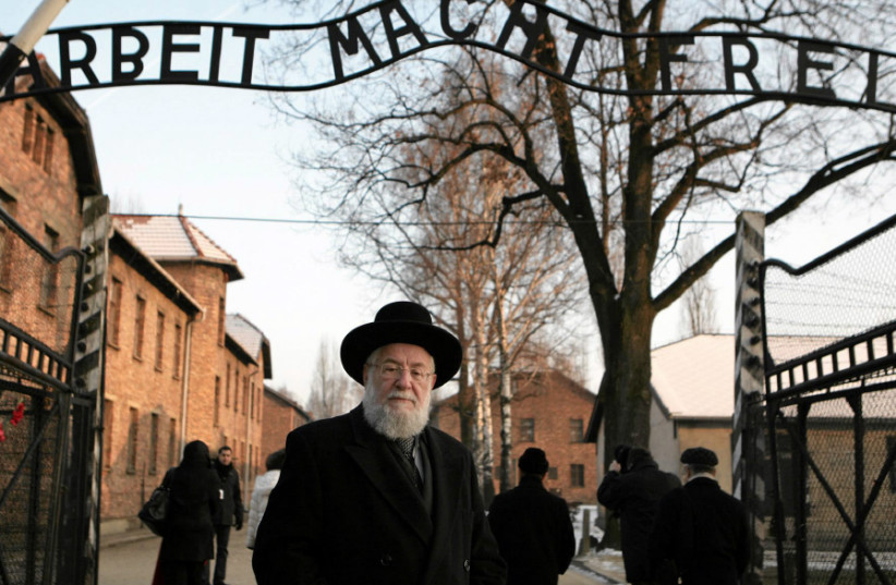 RABBI YISRAEL MEIR LAU stands at the main gate of the former Nazi death camp of Auschwitz with the words ‘Arbeit macht frei’ (Work sets you free), on February 1, 2011 (photo credit: MICHAL LEPECKI/AGENCIA GAZETA/REUTERS)