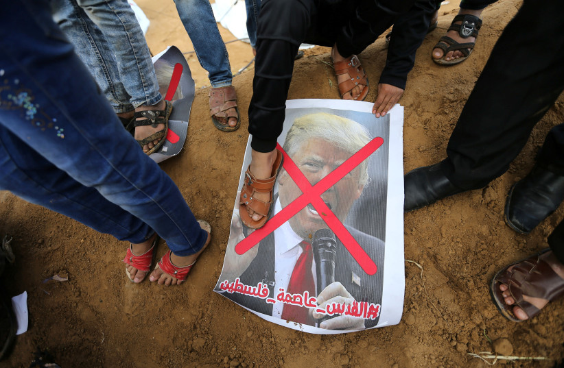 A Palestinian steps on a poster depicting U.S. President Donald Trump during a tent city protest along the Israel border with Gaza, demanding the right to return to their homeland, in the southern Gaza Strip March 30, 2018 (photo credit: IBRAHEEM ABU MUSTAFA / REUTERS)