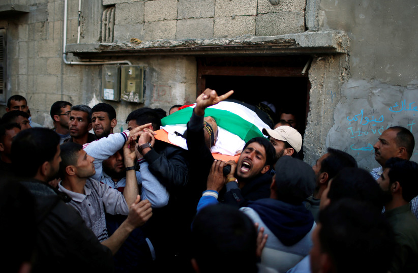 Mourners carry the body of Palestinian Faris al-Reqib, 29, who was killed during clashes at Israel-Gaza border, during his funeral in Khan Younis, in the southern Gaza Strip April 2, 2018. (photo credit: MOHAMMED SALEM/REUTERS)