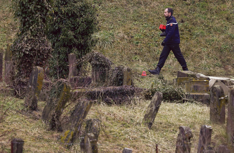 A French Gendarme walks by some of 250 desecrated tombstones at the Sarre-Union Jewish cemetery, near Strasbourg, in this file photo (photo credit: VINCENT KESSLER/ REUTERS)