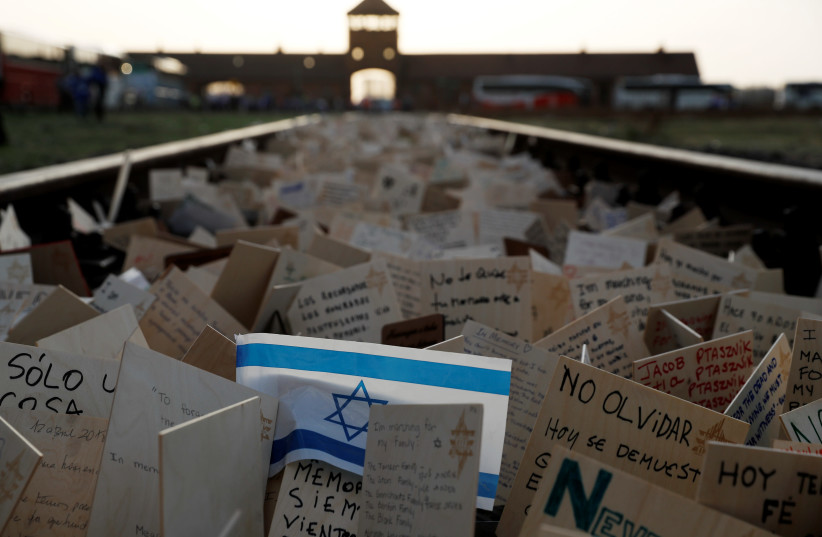 Cards are placed between railway tracks in the former Nazi death camp Auschwitz as people take part in the annual "March of the Living" to commemorate the Holocaust, in Oswiecim, Poland, April 12, 2018.  (photo credit: REUTERS/KACPER PEMPEL)