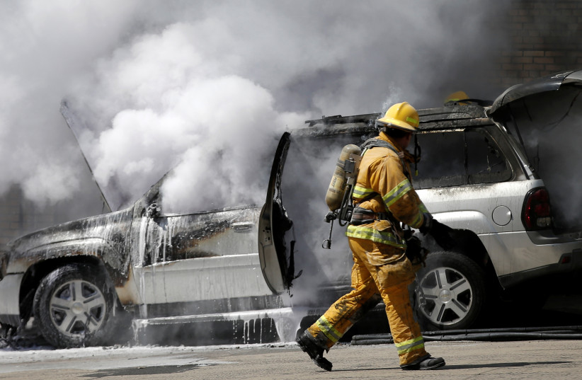 A firefighter approaches a burning car in New York City (photo credit: MIKE SEGAR / REUTERS)
