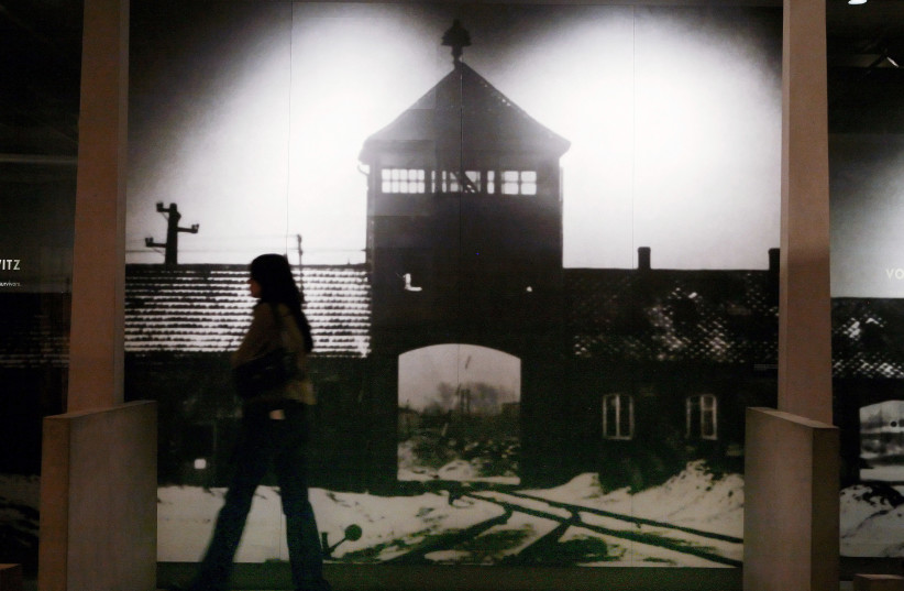 A visitor to the US Holocaust Memorial Museum walks past a mural of the Auschwitz-Birkenau concentration camp in Washington, January 26, 2007 (credit: REUTERS/JIM YOUNG)