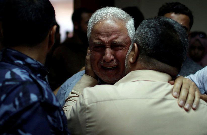 A relative of Palestinian Ahmed al-Rantisi, who was killed during a protest at the Israel-Gaza border, is consoled at a hospital in the northern Gaza Strip May 14, 2018. (photo credit: REUTERS/MOHAMMED SALEM)