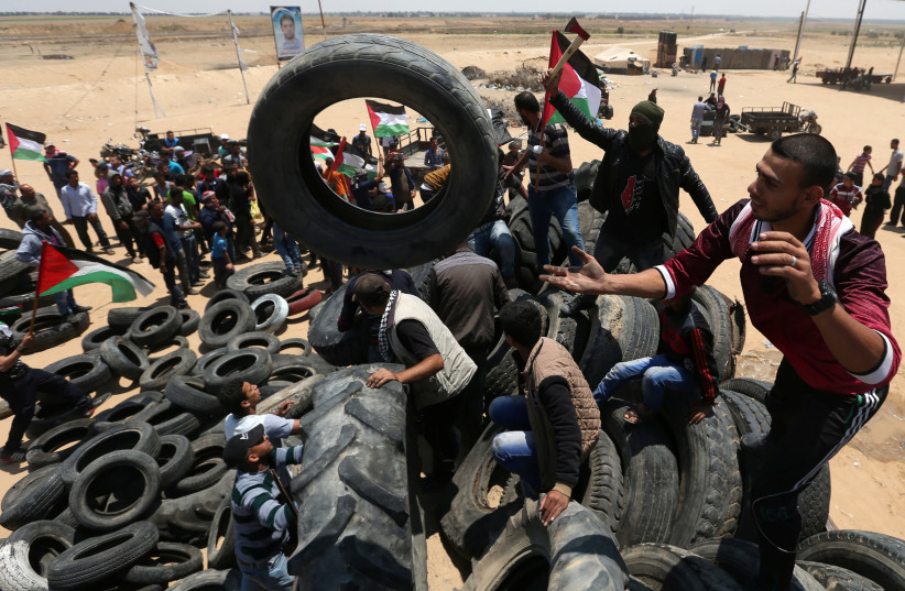 Palestinians collect tires to be burnt during a protest marking the 70th anniversary of Nakba, at the Israel-Gaza border in the southern Gaza Strip May 15, 2018 (photo credit: REUTERS)