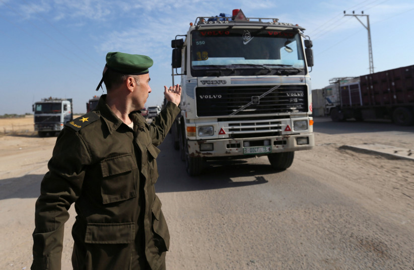 A member of the security forces of the Palestinian Authority gestures as a truck carrying goods arrives at Kerem Shalom crossing in the southern Gaza Strip November 7, 2017.  (credit: REUTERS/IBRAHEEM ABU MUSTAFA)