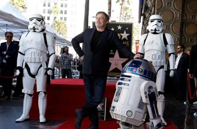 Actor Mark Hamill poses with "Star Wars" characters R2-D2 and Stormtroopers after unveiling his star on the Hollywood Walk of Fame in Los Angeles, California, US, March 8, 2018 (photo credit: MARIO ANZUONI/REUTERS)