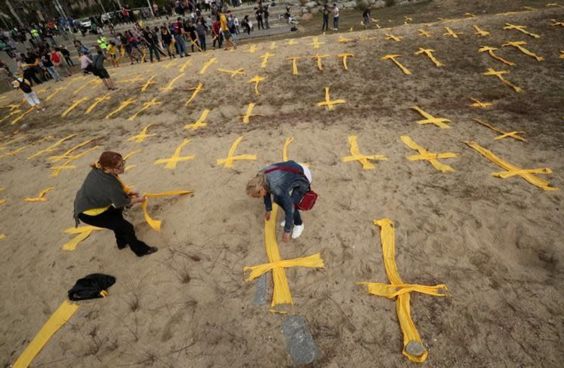Catalan separatist supporters remove yellow crosses after a protest to demand the release of jailed Catalonian politicians, at Mataro's beach, north of Barcelona, Spain May 27, 2018 (photo credit: ALBERT GEA/ REUTERS)