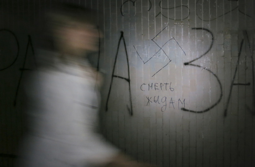 A woman walks past a swastika and the inscription "Death to Jews' painted on a wall in an underpass in Kiev May 29, 2012.  (photo credit: GLEB GARANICH/REUTERS)