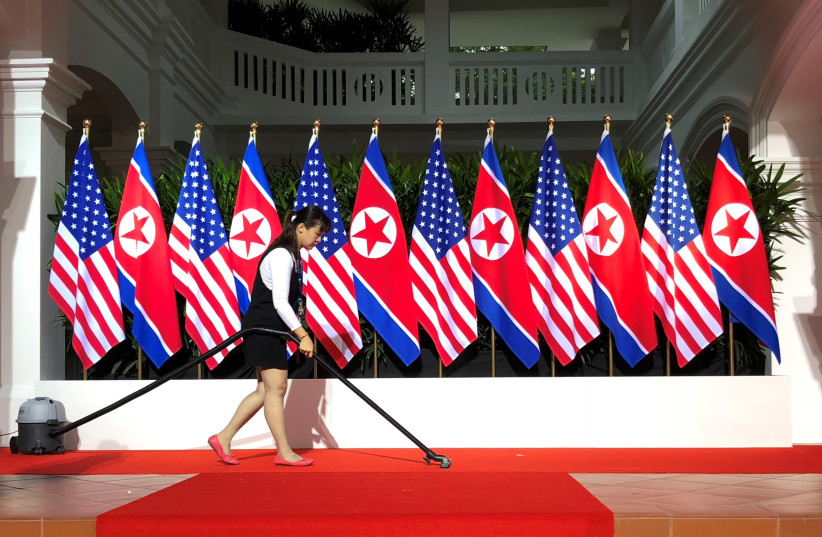 A worker vacuums the stage at the spot where U.S. President Donald Trump and North Korea's leader Kim Jong Un are expected to meet and shake hands for the first time at the start of their summit at the Capella Hotel on Singapore's resort island of Sentosa in Singapore June 12, 2018. (photo credit: JONATHAN ERNST / REUTERS)