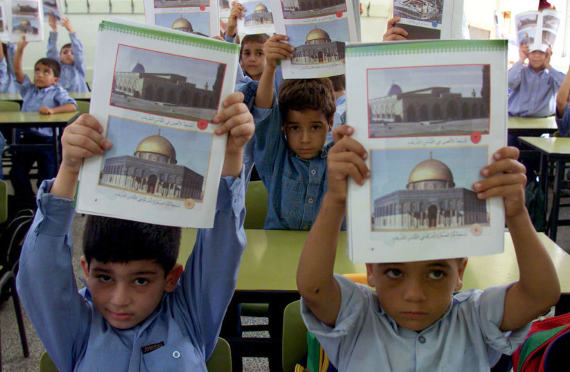 Estudiantes palestinos muestran su nuevo programa educativo palestino al comienzo de su nuevo año escolar en la Franja de Gaza el 7 de septiembre de 2000 (crédito: REUTERS)