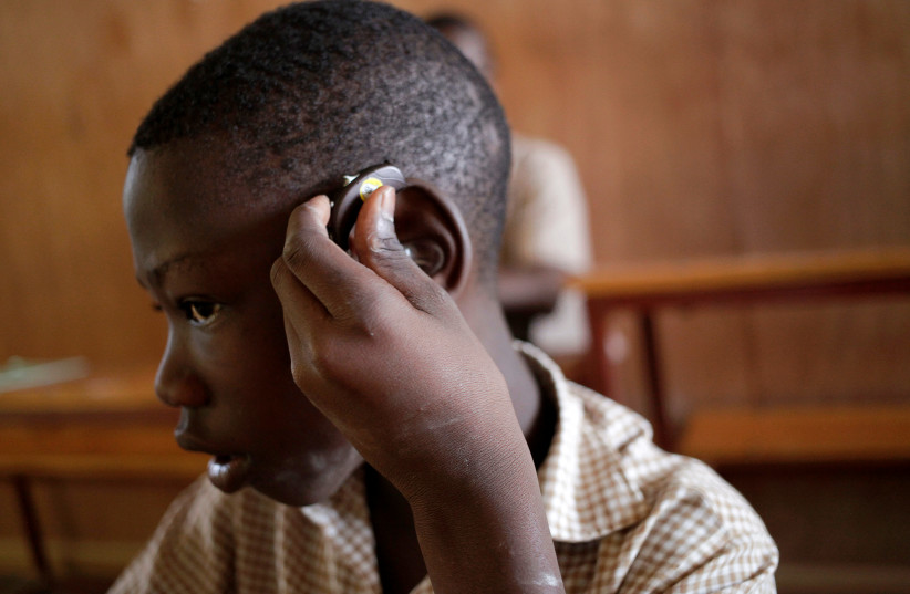 A deaf pupil puts a hearing aid on his ear at the Mission de L'Espoir school in Leveque, Haiti, April 11, 2016. (credit: REUTERS/ANDRES MARTINEZ CASARES)