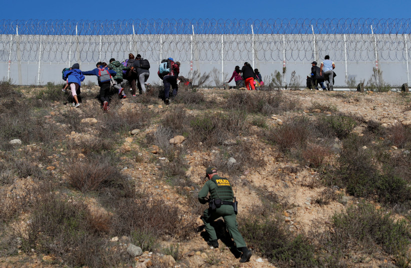 U.S. Customs and Border Protection (CBP) officials detain a group of migrants, part of a caravan of thousands from Central America trying to reach the United States, after they crossed illegally from Mexico to the U.S, as seen from Tijuana, Mexico, December 15, 2018. (credit: CARLOS GARCIA RAWLINS/ REUTERS)