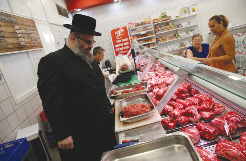KOSHER INSPECTOR Aaron Wulkan examines meat to ensure that the food is stored and prepared according to Jewish regulations and customs in a Bat Yam store. (credit: BAZ RATNER/REUTERS)