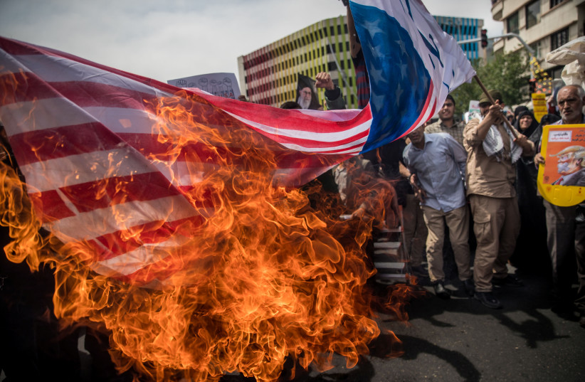 Iranians burn a U.S. flag during a protest against President Donald Trump's decision to walk out of a 2015 nuclear deal, in Tehran, Iran, May 11, 2018.  (photo credit: REUTERS)