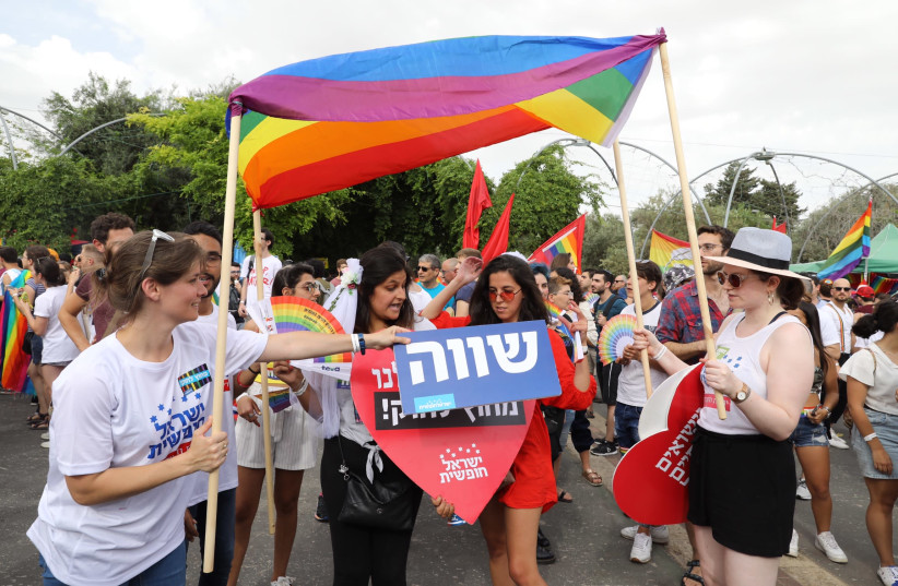 Jerusalem Pride parade attendees stand under a make-shift Chuppah made out of a Pride flag (photo credit: MARC ISRAEL SELLEM/THE JERUSALEM POST)