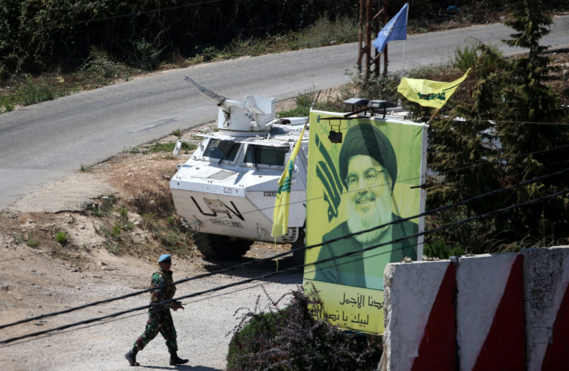 A U.N peacekeeper of the United Nations Interim Force in Lebanon (UNIFIL) walks near a poster depicting Lebanon's Hezbollah leader Sayyed Hassan Nasrallah (photo credit: REUTERS)