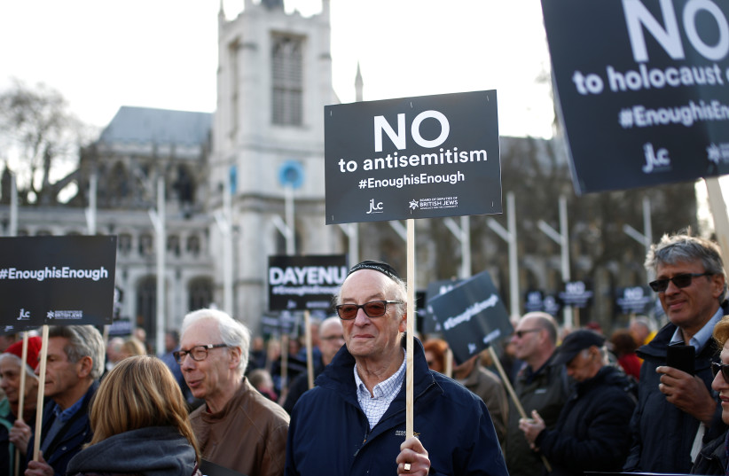 Protesters hold placards and flags during a demonstration, organised by the British Board of Jewish Deputies for those who oppose antisemitism, in Parliament Square in London.  (credit: HENRY NICHOLLS/REUTERS)