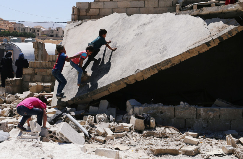 Syrian refugee kids play on a rubble of dismantled concrete huts at a makeshift Syrian refugee camp in the Lebanese border town of Arsal, Lebanon (photo credit: REUTERS/MOHAMED AZAKIR)