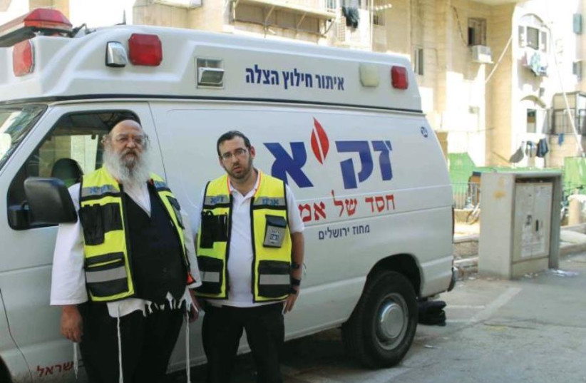 ZAKA first responders Yossi Frankel (right) and Benzi Oring with one of the organization’s emergency vehicles (credit: SAM SOKOL)