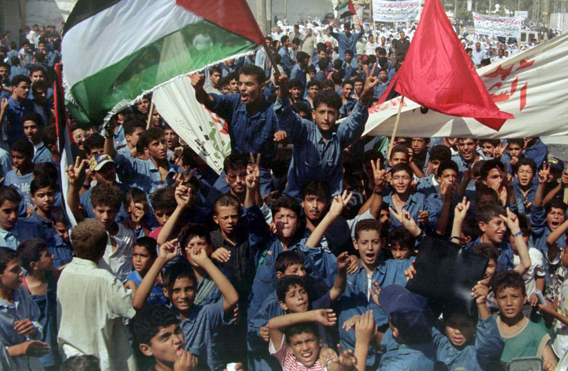 Niños escolares palestinos cantan consignas durante una manifestación el 28 de agosto de 1997 en la Franja de Gaza en protesta por los recortes presupuestarios de la UNRWA. (Crédito: REUTERS)