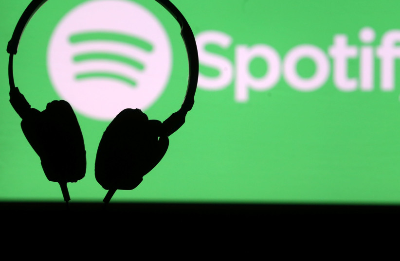 A headset is seen in front of a screen projection of Spotify logo, in this picture illustration (credit: REUTERS)