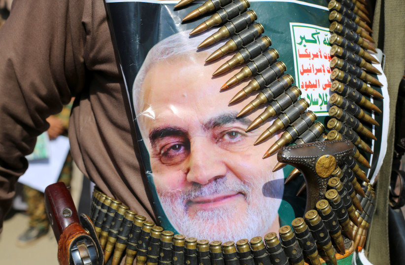 A supporter of the Houthis has a poster attached to his waist of Iranian Major-General Qassem Soleimani, head of the elite Quds Force, who was killed in an air strike at Baghdad airport, during a rally to denounce the U.S. killing, in Saada, Yemen January 6, 2020. The writing on the poster reads: "G (photo credit: REUTERS/NAIF RAHMA)