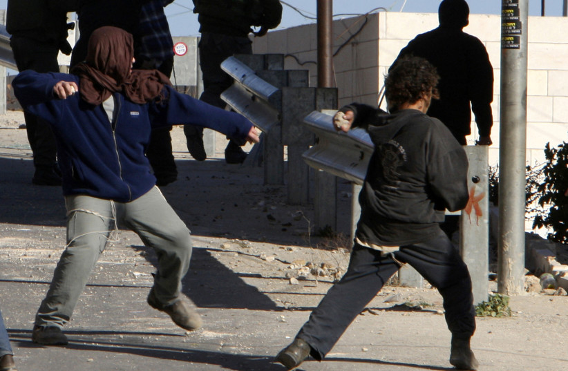 Masked Jewish settler throws stones at Palestinian houses, 2008 (credit: NAYEF HASHLAMOUN/REUTERS)