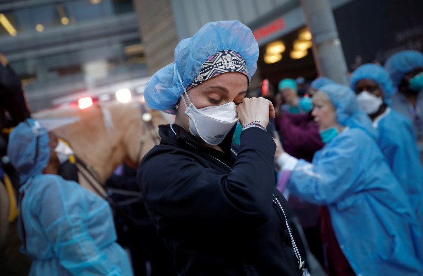 A nurse wipes away tears as she stands outside NYU Langone Medical Center on 1st Avenue in Manhattan, U.S. April 16, 2020.  (photo credit: REUTERS/MIKE SEGAR)