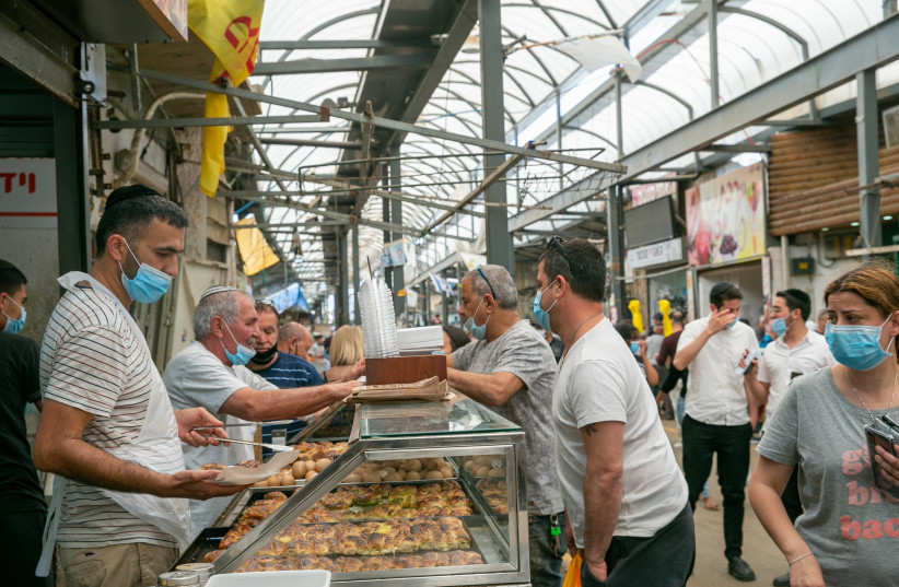 Israelis wear face masks for fear of the coronavirus as they walk through the market in Ramle on May 1, 2020. Daily Isaraeli life is slowly getting back after the outbreak of the Coronavirus. (photo credit: YOSSI ALONI/FLASH90)