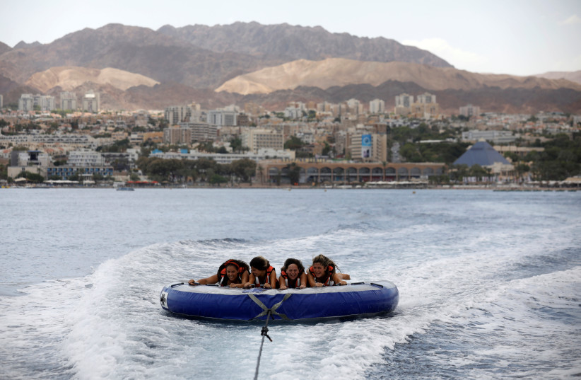 Teenagers hold onto an inflatable water sport raft in the Red Sea, in Eilat (credit: AMIR COHEN/REUTERS)