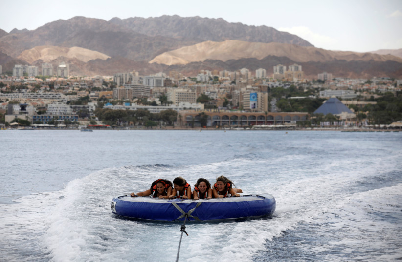 Teenagers hold onto an inflatable water sport raft in the Red Sea, in Eilat