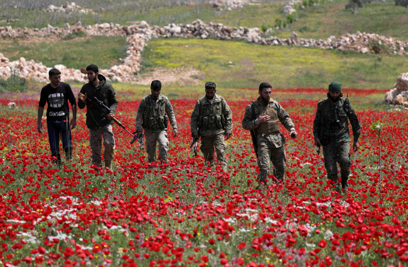 TURKEY-BACKED Syrian rebel fighters walk through a field of flowers in Idlib’s southern countryside, in Syria in April