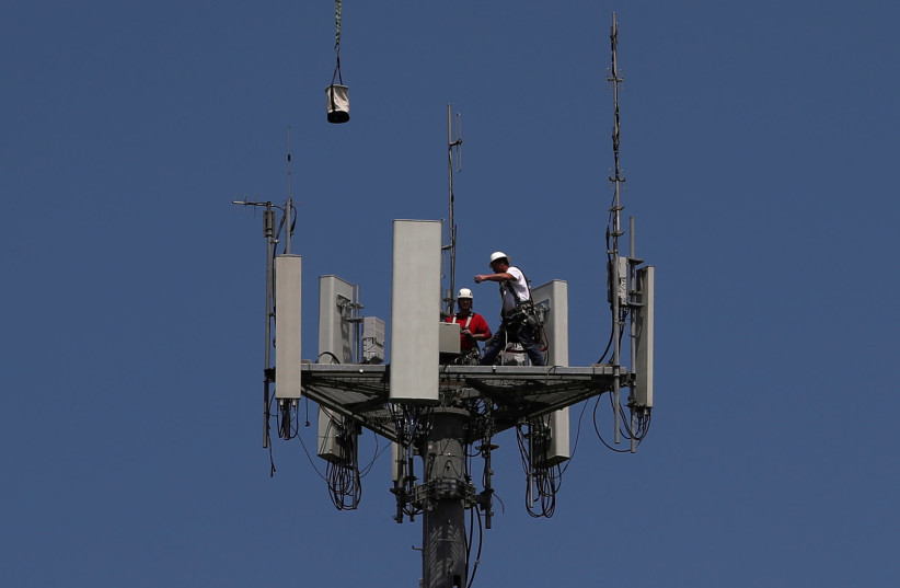 Workers install 5G telecommunications equipment on a T-Mobile tower in Seabrook, Texas. May 6, 2020 (photo credit: REUTERS/ADREES LATIF)