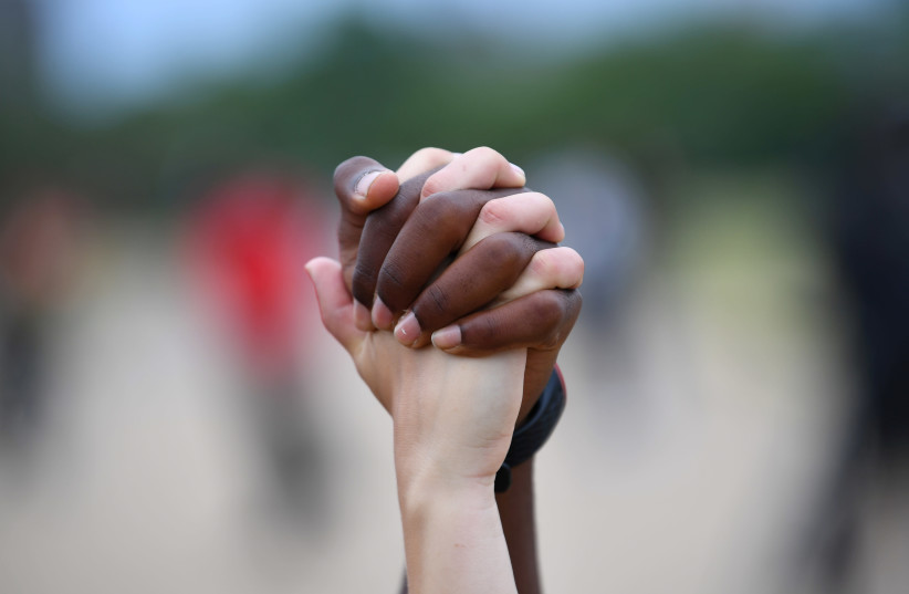 A man and a woman hold hands aloft in Hyde Park during a ''Black Lives Matter'' protest following the death of George Floyd who died in police custody in Minneapolis, London, Britain, June 3, 2020 (credit: REUTERS/DYLAN MARTINEZ)