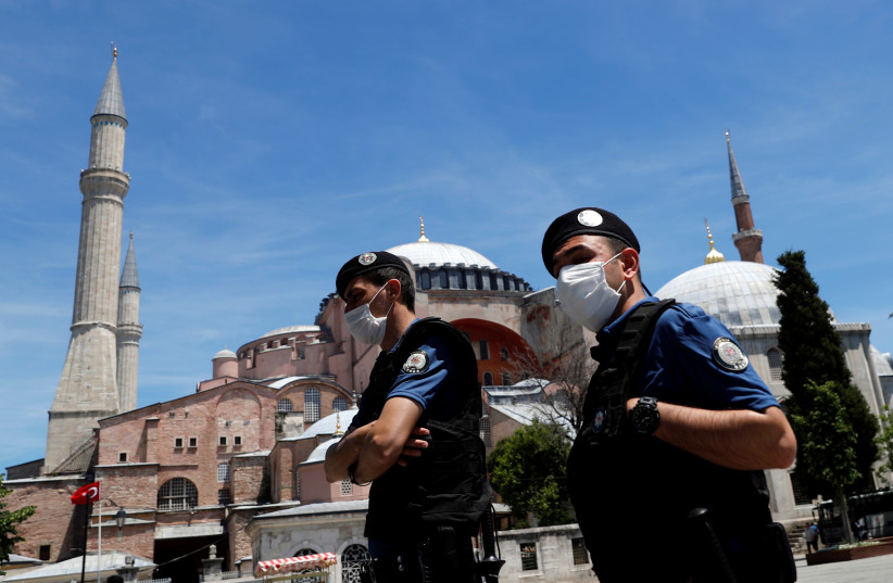 Turkish police officers wearing face masks, with the Byzantine-era monument of Hagia Sophia, now a museum, in the background, patrol at touristic Sultanahmet Square following the coronavirus disease (COVID-19) outbreak, in Istanbul, Turkey, June 5, 2020 (credit: REUTERS/MURAD SEZER)