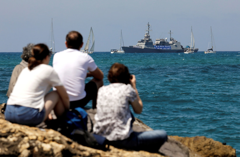 People watch an Israeli Navy corvette vessel, in the Mediterranean Sea during a marine show as part of the celebrations for Israel's Independence Day marking the 70th anniversary of the creation of the state, in Tel Aviv, Israel April 19, 2018 (photo credit: REUTERS/AMIR COHEN)