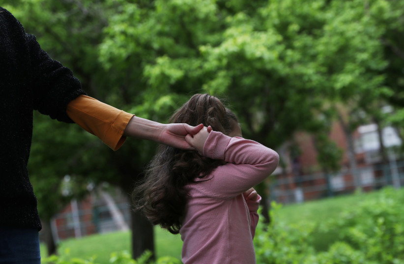 Susana Cristo Anzola is pulled by her daughter Olivia, a 4-year-old on the autism spectrum, to enter a closed playground during the lockdown amid the coronavirus disease (COVID-19) outbreak in Madrid, Spain, April 9, 2020. (photo credit: REUTERS/SUSANA VERA)
